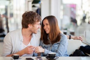 Candid image of young couple smiling in a coffee shop. Shallow DOF, focus on man's eyelash.